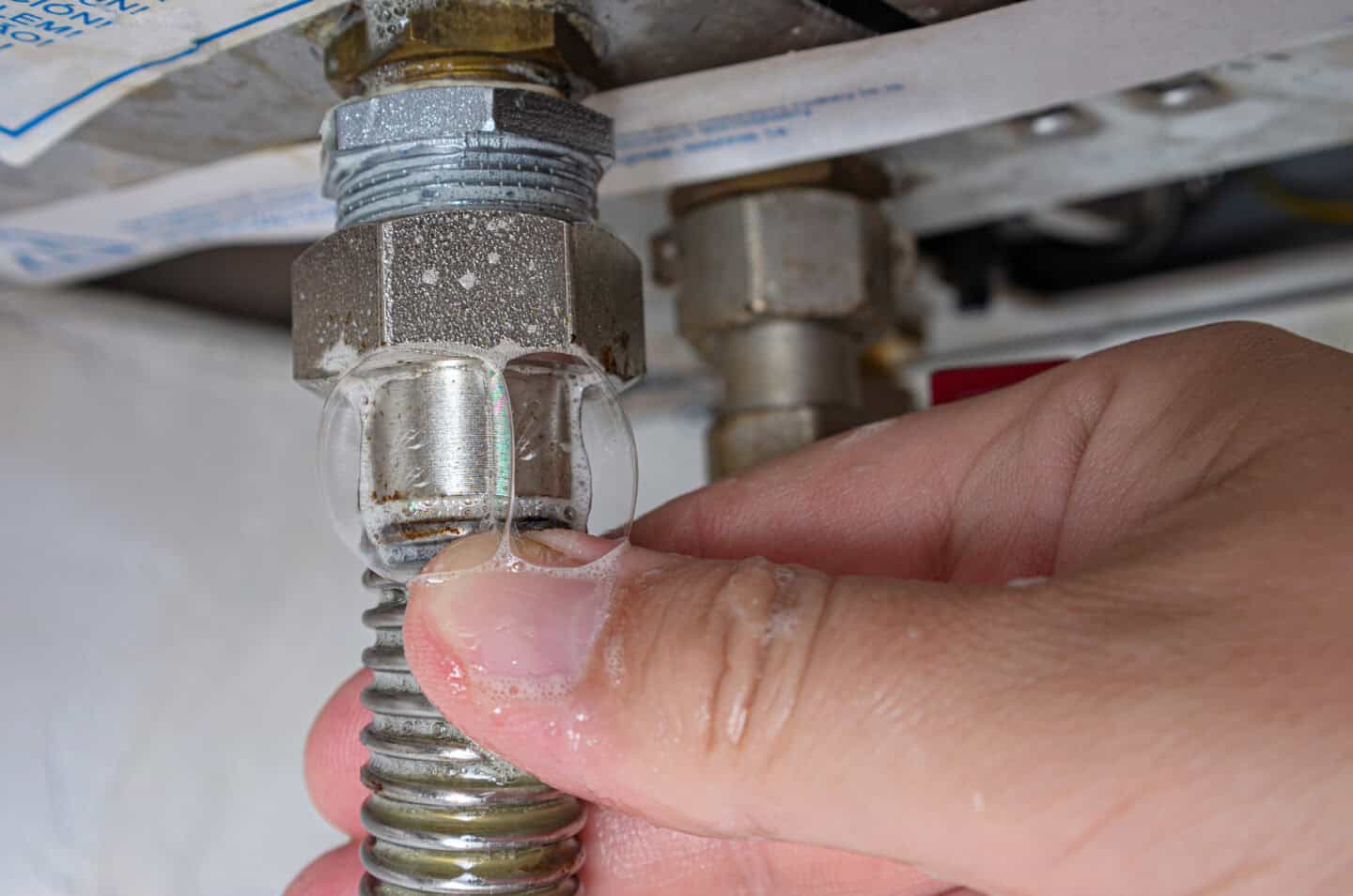 Gas leak at home boiler room. Inflating bubbles of soap mixture applied to the threaded joint on the gas flexible pipe indicate a gas leak. Preventing a gas explosion disaster.